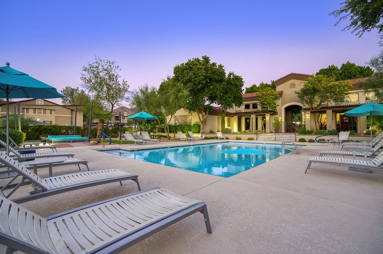 Luxurious Scottsdale condos with a swimming pool, lounge chairs, umbrellas, and lush greenery, perfect for groups and golf enthusiasts.