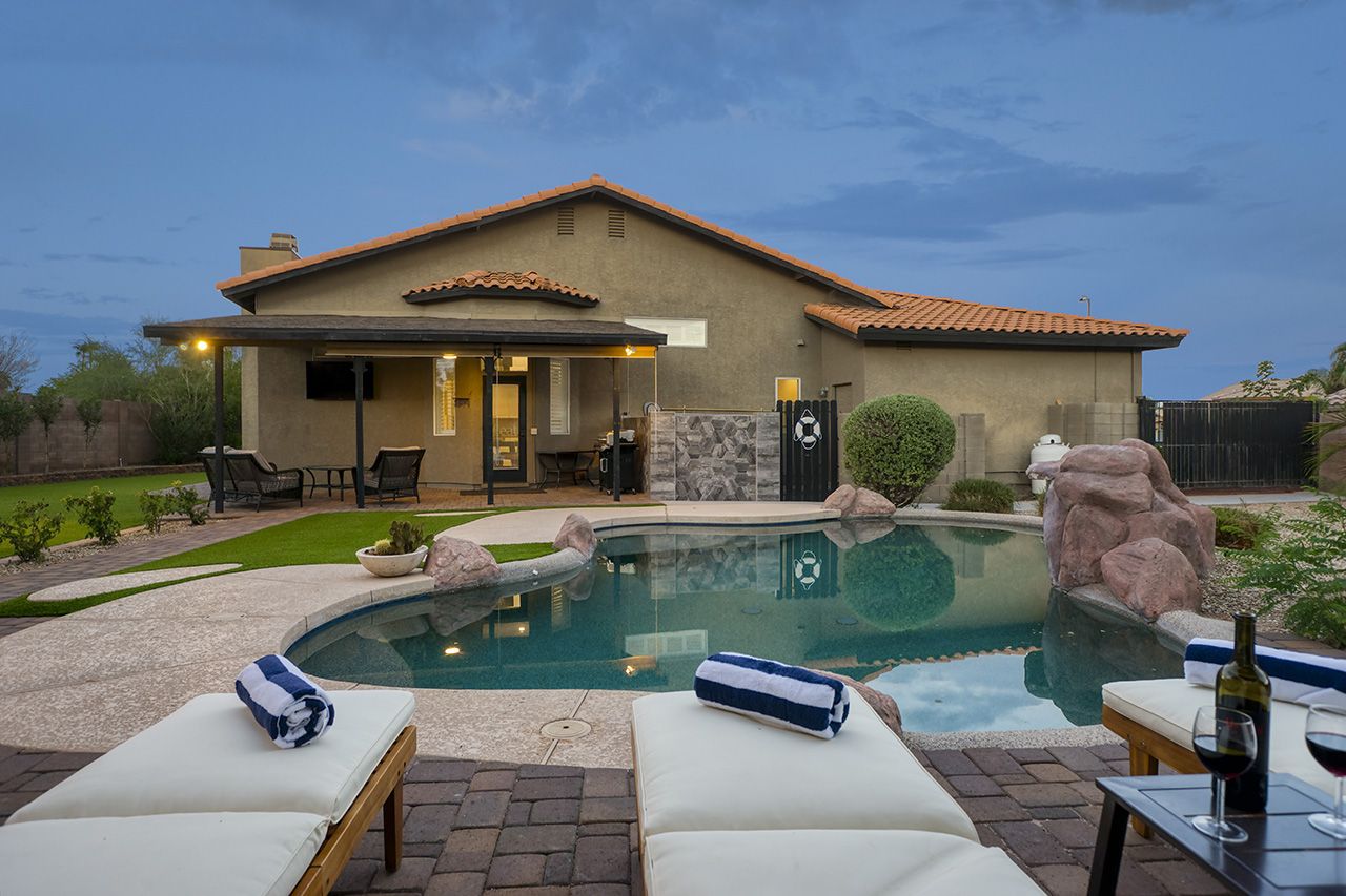 Luxury Scottsdale vacation home with a private pool, outdoor seating, and a backyard view of the house at dusk.
