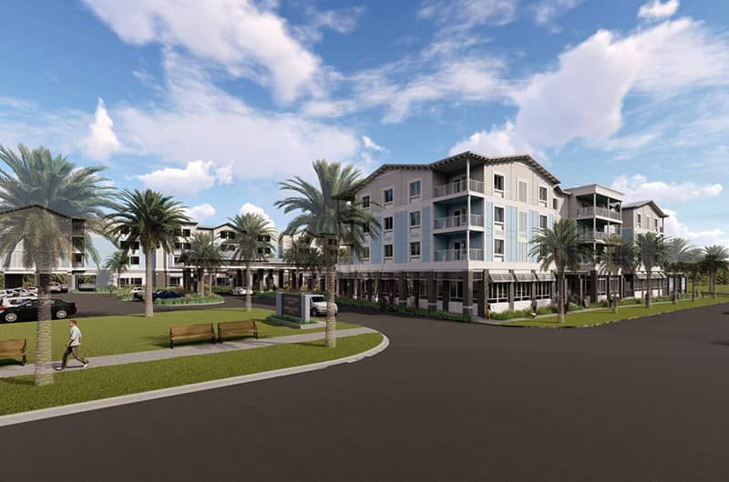 Modern multi-story hotel with palm trees, green lawns, benches, and parking area, set against a blue sky with clouds.