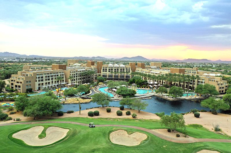 Aerial view of Desert Ridge Resort & Spa with multiple pools, lush greenery, a golf course, and a large hotel complex in Arizona.