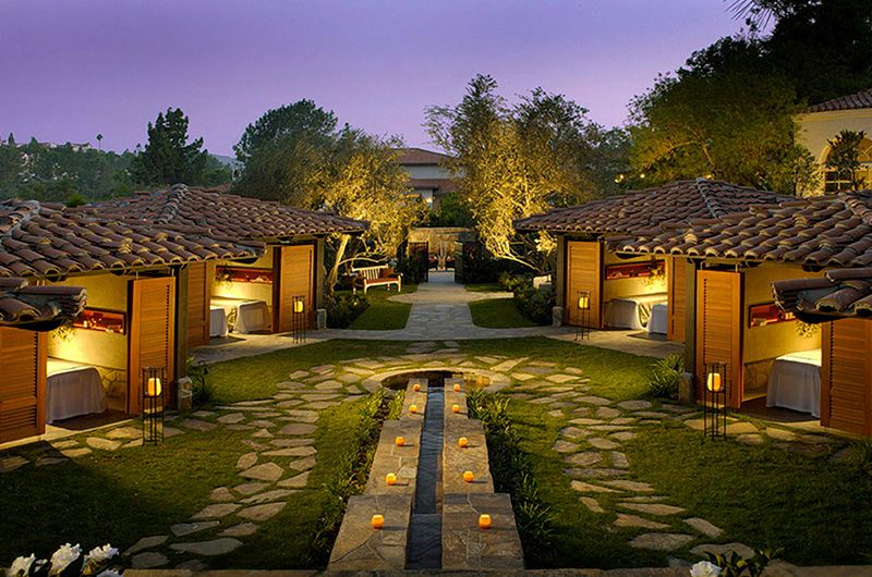 Night view of luxury outdoor dining cabanas at Rancho Bernardo Inn with warm lighting, lush greenery, and a serene ambiance.