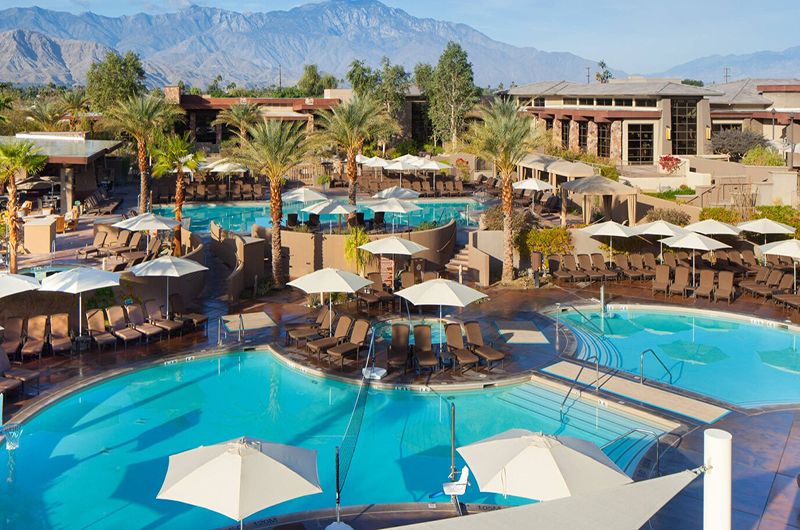 The Westin Desert Willow Villas Luxury resort pool area at The Westin Desert Willow Villas with palm trees, lounge chairs, umbrellas, and mountain views.