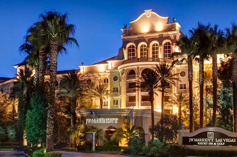 JW Marriott at TPC Las Vegas Luxurious JW Marriott hotel at TPC Las Vegas, illuminated at night with palm trees in the foreground.