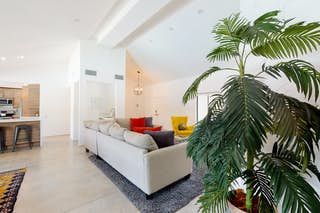 Palm Springs Mediterranean Masterpiece Luxurious Palm Springs Mediterranean-style living room with modern furniture, vibrant cushions, and lush green plant.