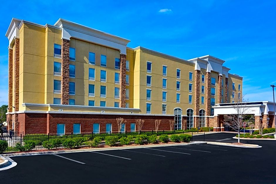 Hoover Hampton Inn & Suites hotel in Hoover, Alabama, with a parking lot and landscaped surroundings under a bright blue sky.