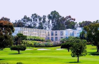 Luxurious Hilton La Jolla Torrey Pines hotel with ocean views, surrounded by lush greenery and a golf course.