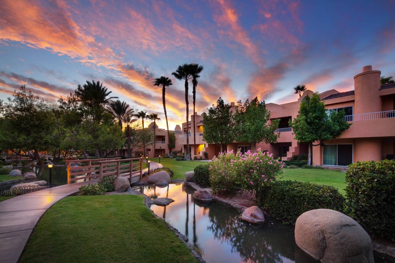 The Westin Mission Resort Villas Scenic view of the Westin Mission Hills Villas in Palm Springs at sunset, featuring lush gardens, palm trees, and a tranquil waterway.