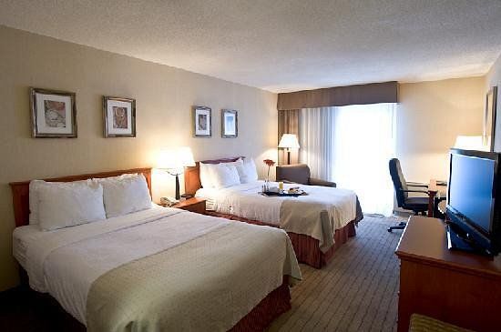 Allure Hotel and Conference Center Interior of a hotel room with two beds, a TV, a desk, and a window with curtains, in a modern, comfortable setting.