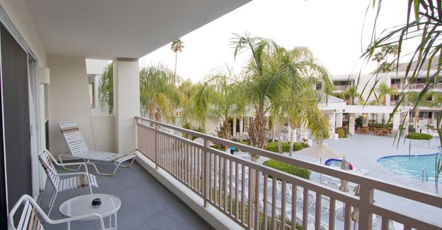 Palm Canyon Resort Balcony view overlooking palm trees, pool, and resort buildings at Palm Canyon Resort in Palm Springs, ideal for golf vacations.