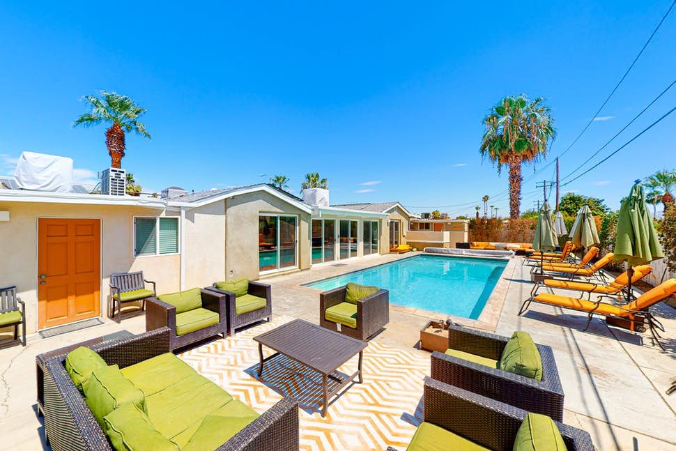 Sunsational Views Luxurious Palm Springs retreat with two vacation homes, a swimming pool, outdoor seating, palm trees, and sunny weather.