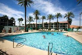 Swimming pool at Virgin River Hotel in Mesquite, surrounded by palm trees and hotel buildings, with people enjoying the water.