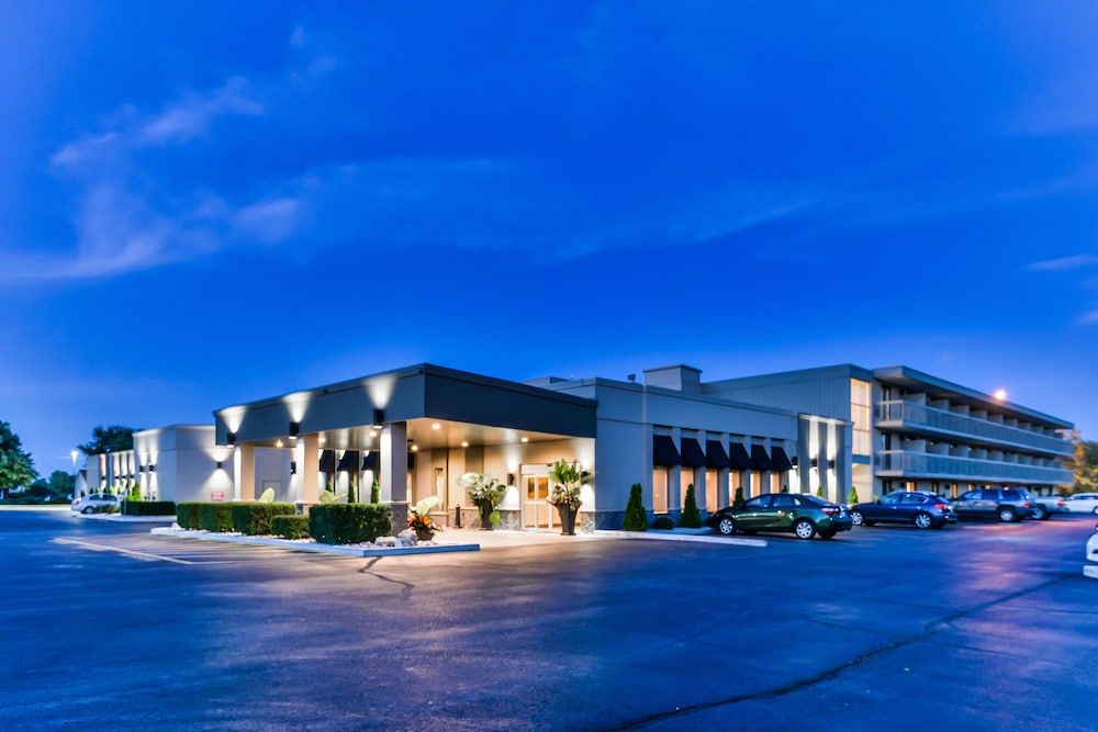 Best Western Leamington Exterior view of the Best Western Leamington hotel at dusk, with lit entrance, parked cars, and a clear blue sky.