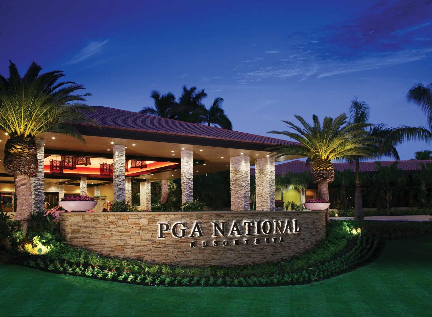 PGA National Resort Night view of PGA National Resort & Spa in Palm Beach with illuminated entrance, palm trees, and lush landscaping.