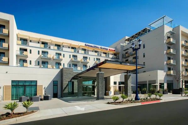 Exterior view of SpringHill Suites by Marriott in Oceanside, featuring modern architecture, balconies, and a clear blue sky.