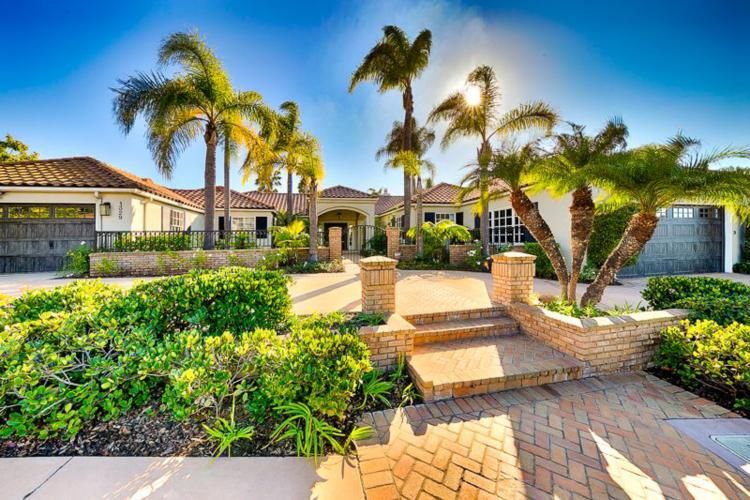Luxurious La Jolla home with palm trees, lush landscaping, and panoramic ocean views, perfect for upscale living and golfing.