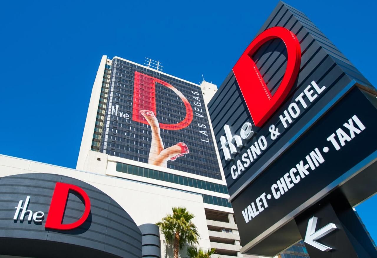 The D Las Vegas Exterior view of The D Las Vegas hotel with signage for casino, valet, check-in, and taxi services against a clear blue sky.