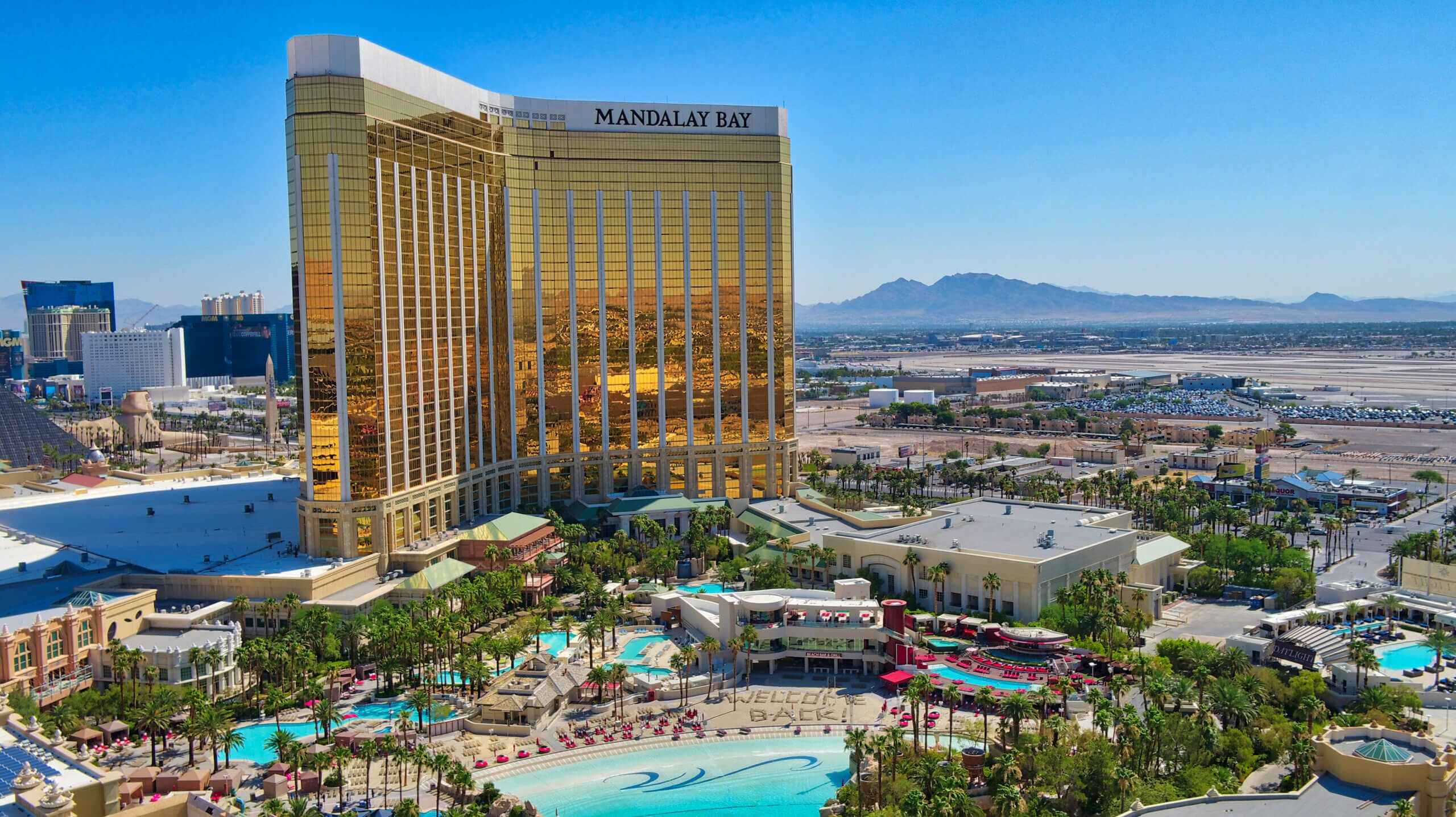 Mandalay Bay Resort and Casino Aerial view of Mandalay Bay Resort and Casino in Las Vegas with a golden glass exterior, pool area, and surrounding desert landscape.