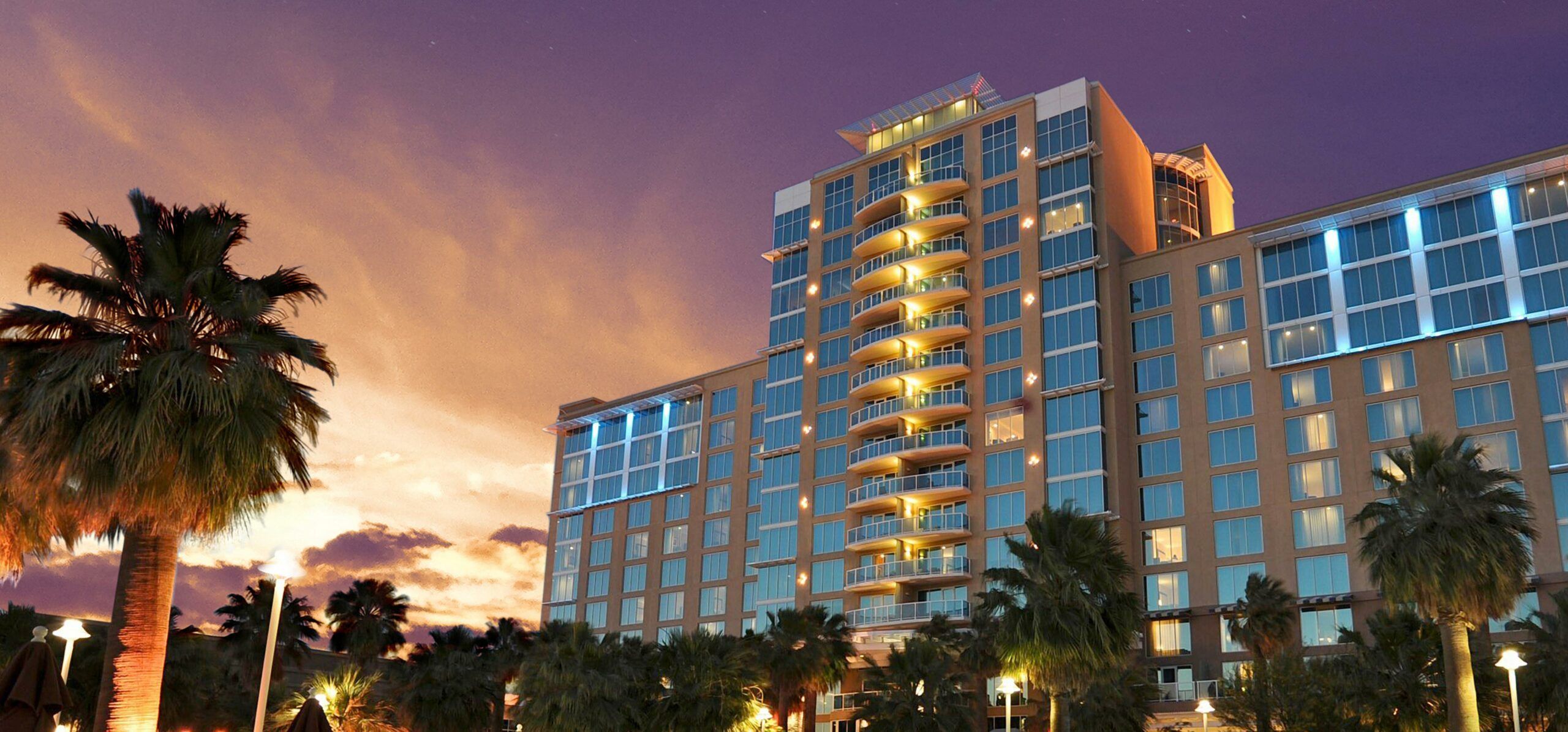 AGUA CALIENTE RESORT CASINO SPA RANCHO MIRAGE Luxury hotel building at Agua Caliente Resort Casino Spa in Rancho Mirage during sunset, with illuminated balconies and palm trees.
