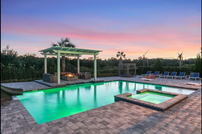 Luxury private pool area at sunset with lounge chairs, fire pit, and scenic views in Orlando vacation homes.