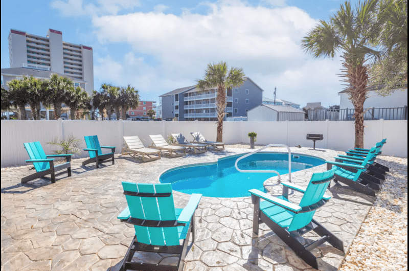 Sunrise on Sunset Beachfront remodeled house with private pool, surrounded by palm trees, near golf courses, under a blue sky with clouds.