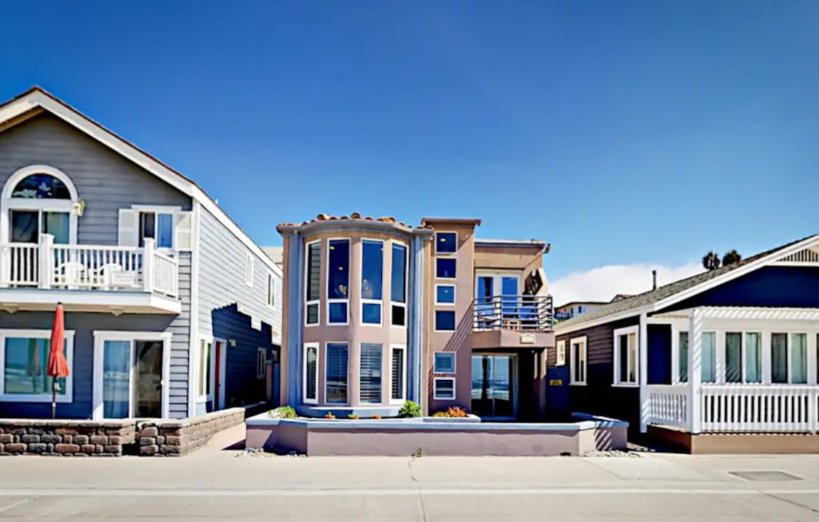 Luxury beachfront house in Oceanside, CA with modern interiors, large windows, and ocean views, surrounded by neighboring homes.