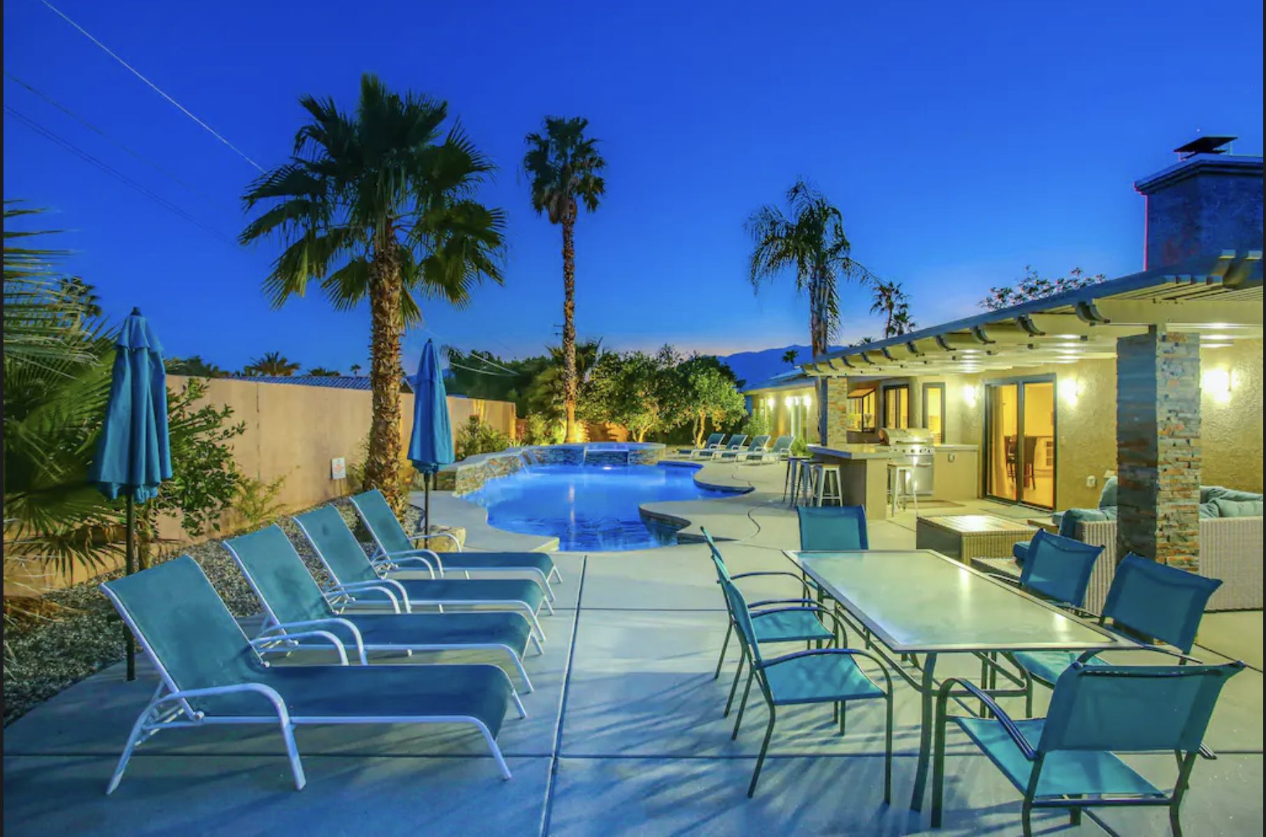 California Vacation Villa - Palm Springs, CA Luxurious California vacation villa in Palm Springs with pool, spa, firepit, outdoor dining, and palm trees at dusk.
