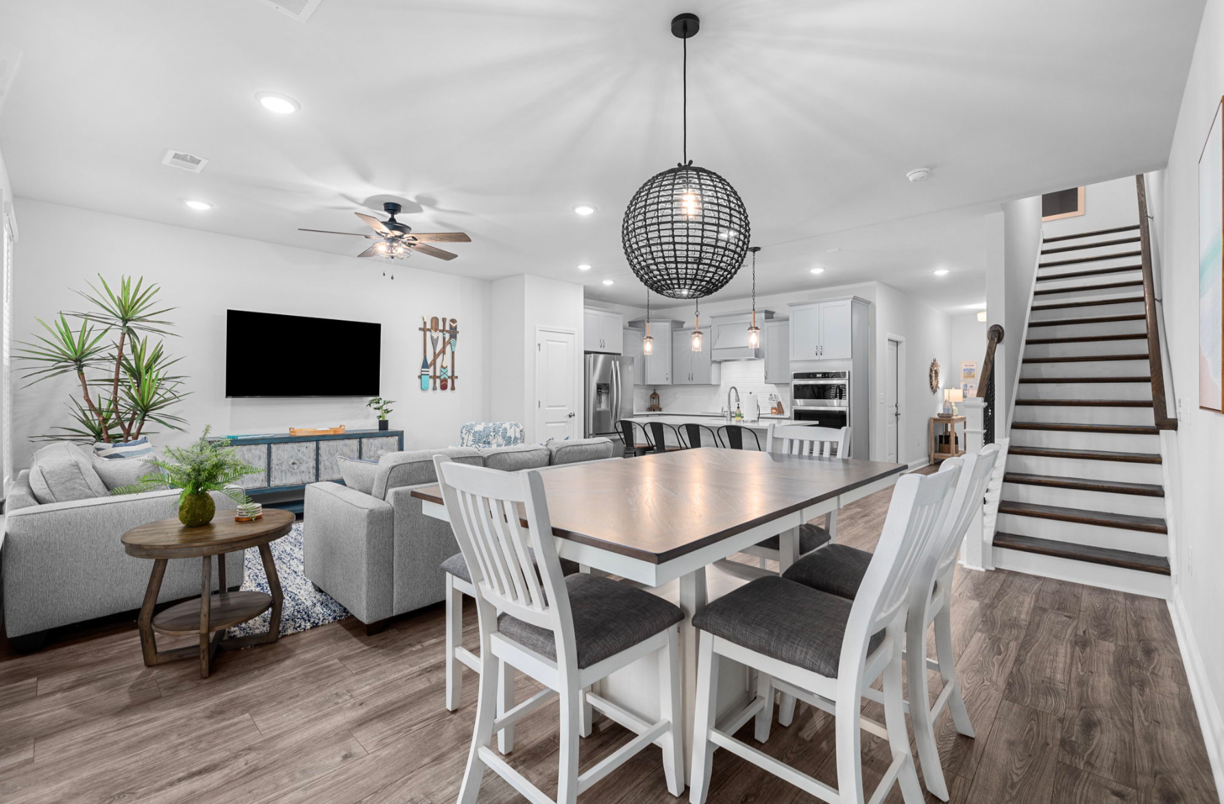 Barefoot Getaway II Modern, open-concept living and dining area in a luxury Myrtle Beach townhome with white cabinetry, hardwood floors, and stylish decor.