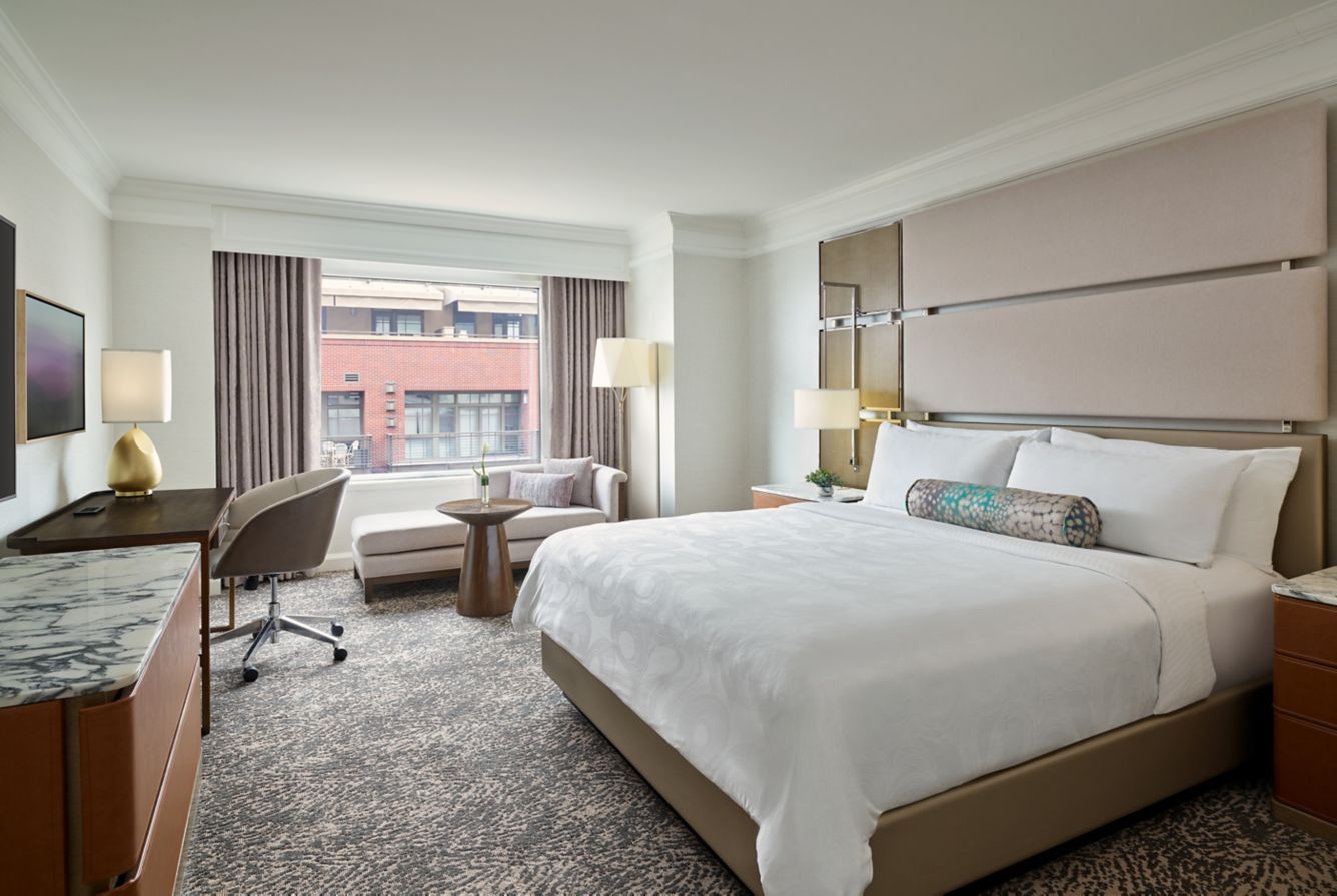 Luxurious hotel room at Hotel Clio in Cherry Creek with a king-size bed, sitting area, and modern decor, featuring a large window.