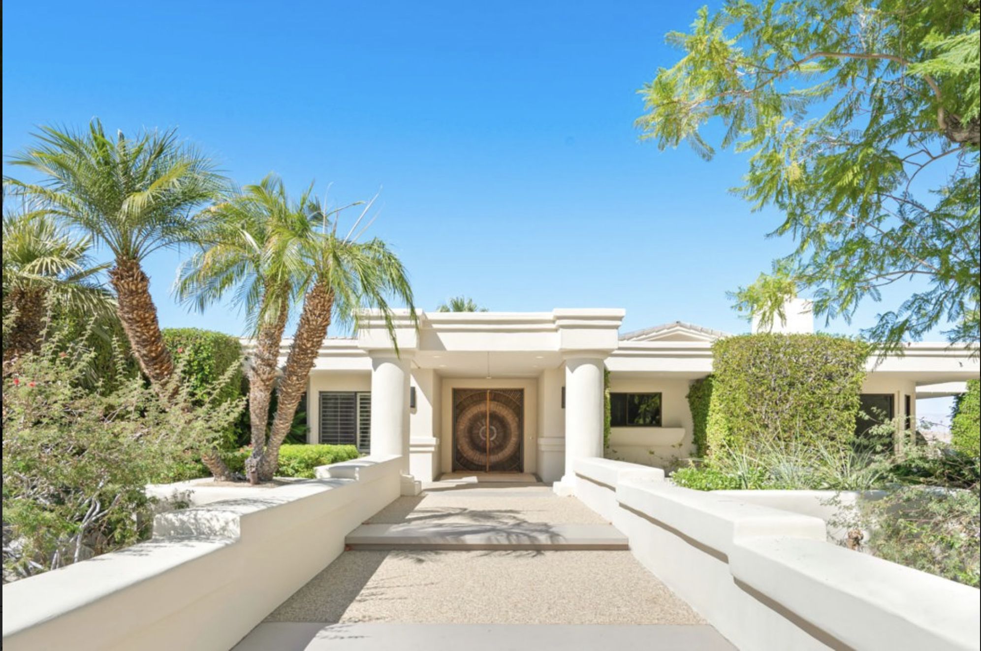 La Paz Estate Luxury white estate with palm trees, lush greenery, and a grand entrance under a clear blue sky, perfect for golf vacations.