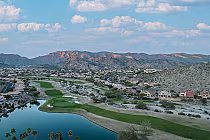 Aerial view of Foothills Golf Club in Phoenix, featuring lush green fairways, a water hazard, residential homes, and mountainous backdrop.