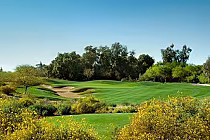 Beautiful golf course at the Legacy Golf Resort in Phoenix with lush green fairways, sand traps, and trees under a clear blue sky.