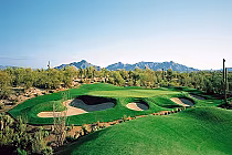 A scenic view of Legend Trail Golf Club in Scottsdale, Arizona, featuring lush green fairways, sand bunkers, desert plants, and mountains in the background.
