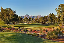 Scenic view of McCormick Ranch golf course with lush green fairways, trees, desert landscaping, and mountains in the background.