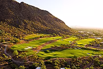 A scenic golf course nestled in the mountains of Scottsdale, with lush green fairways, sand traps, and surrounding desert landscape.