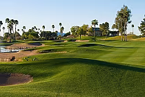 Scenic golf course at Superstition Springs with lush green fairways, palm trees, sand bunkers, and a water hazard under a clear sky.