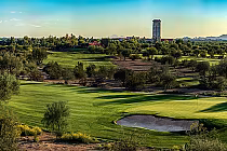 Scenic view of Talking Stick Golf Club's North and South courses with lush green fairways, trees, and a sand bunker, under a clear sky.