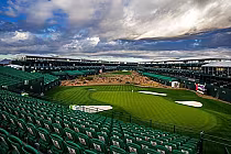 View of TPC Scottsdale Stadium Course with green fairways, sand traps, and grandstands under a cloudy sky, ideal for golf fans.