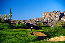 Challenging desert golf course at Gold Canyon, AZ, with green fairways, sand bunkers, desert plants, and scenic mountain views.