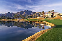 Scenic view of La Quinta Jack Nicklaus golf course with mountains, palm trees, water hazard, and well-maintained green grass.