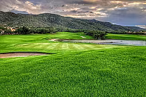 Beautiful golf course at Arizona National with lush green fairways, water hazards, surrounded by mountains and scenic natural beauty.