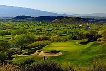 Scenic view of Ventana Canyon Golf course with lush green fairways, trees, and sand traps, set against Santa Catalina Mountains.