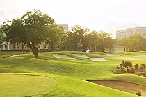 Luxurious golf course at Reunion Resort with lush green fairways, sand traps, and trees, under bright sunlight.