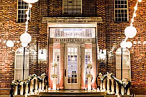 Elegant brick building entrance of Wentworth Golf Club decorated with white flowers, candles, and string lights for an event.