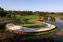 Scenic view of Mission Inn El Campion golf course with lush green fairways, palm trees, and a water hazard under a clear blue sky.