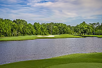 Scenic view of Arnold Palmer's Cotton Creek Golf Course in Gulf Shores, Alabama, featuring lush green fairways, sand bunkers, and a water hazard.