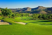 Scenic view of Maderas Golf Club in San Diego with lush green fairways, trees, sand bunkers, and rolling hills in the background.