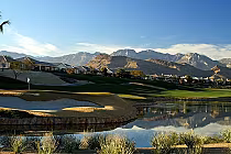 Scenic view of Siena Golf Club with lush green fairways, water hazards, residential homes, and mountain backdrop under a clear blue sky.