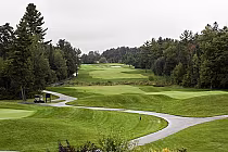 Scenic view of a golf course at National Pines Golf Club in Innisfill, ON, featuring lush green fairways, trees, and a winding cart path.