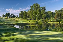Scenic golf course at Trillium Wood Golf Club in Ontario with lush green fairways, trees, water hazards, under a blue sky.