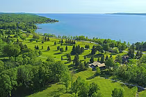 Aerial view of Legacy Ridge Golf Club with lush green fairways, trees, and a large lake in Ontario, showcasing a high-end golf course.